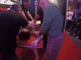 Une groupe de personnes massage ce jeune et tattoed dame à la même temps en publique